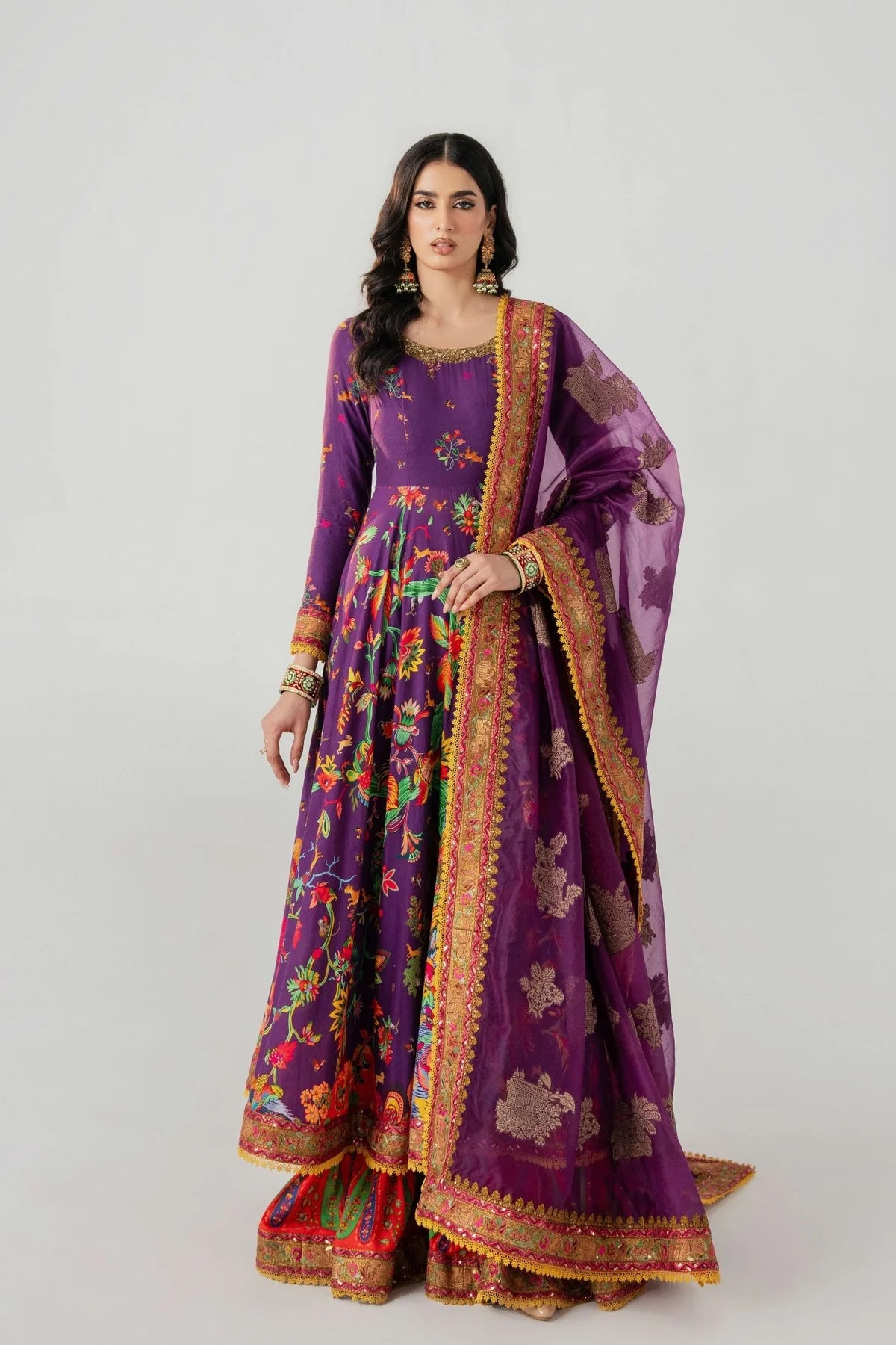 Woman wearing a traditional purple outfit with floral patterns on a white background.
Mihrab By Ruuposh Collection 05
