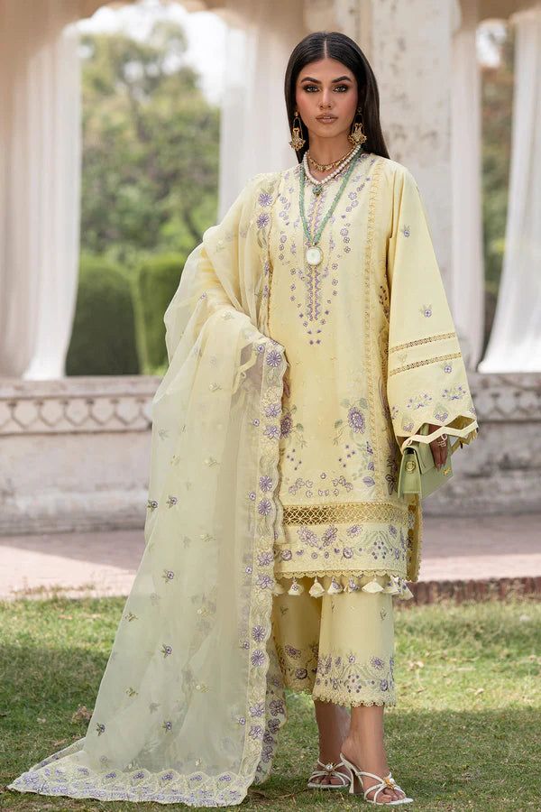Woman in a light yellow embroidered traditional outfit standing outdoors.