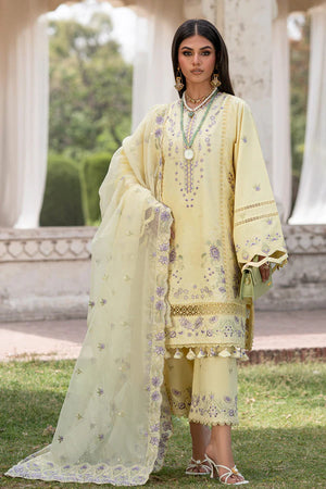 Woman in a light yellow embroidered traditional outfit standing outdoors.