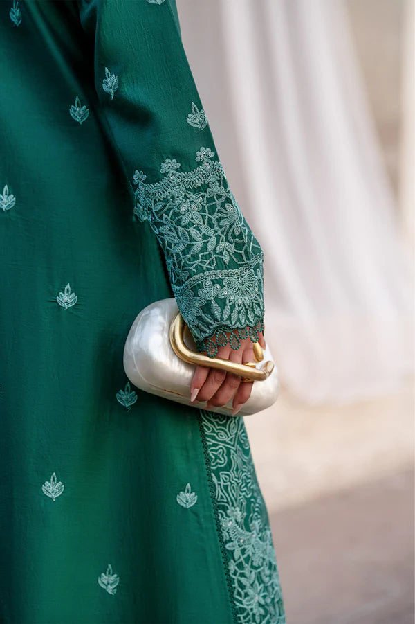 Green embroidered garment with a hand holding a white clutch.