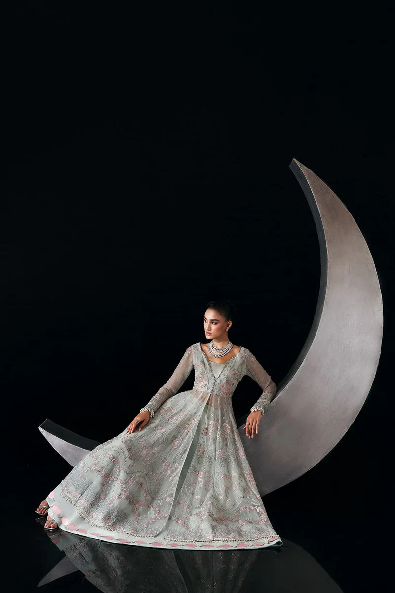 Woman in a light green embroidered dress sitting on a large crescent moon against a black background.
Verae By Ruuposh Collection 06